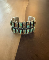Silver bracelet with turquoise stones on a wooden surface