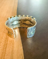 Silver bracelet with intricate designs on a wooden surface