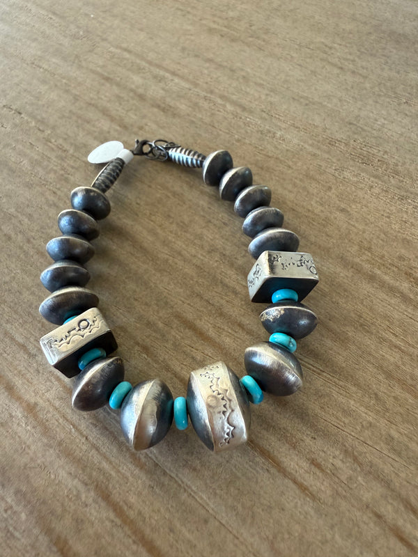 Bracelet with metallic beads and turquoise accents on a wooden surface