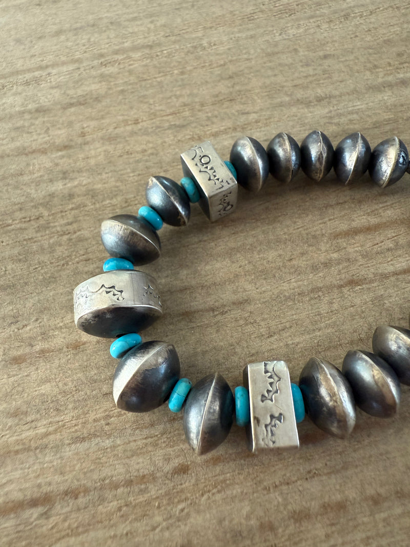 Bracelet with silver beads and turquoise accents on a wooden surface